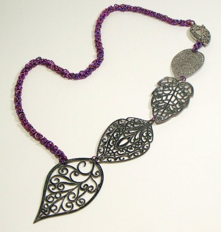 This asymmetric neckpiece shows an anodized chain and naturally colored focal.